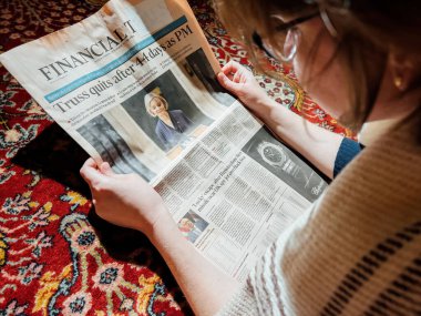 LONDON, ENGLAND - 20 EKİM: oturma odasında okuyan kadın Financial Times 'ın ön sayfasında Başbakan Liz Truss' un istifasını duyurdu, Westminster 'da