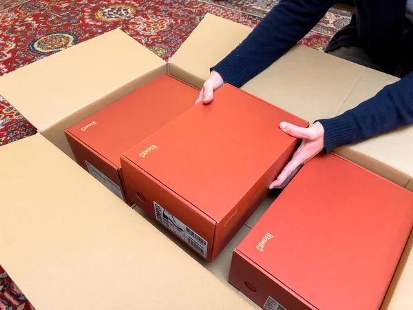 英国伦敦 2022年10月21日 女子拆箱纸板箱电子商务互联网订单与三双红色露营鞋 从一个更大的盒子 — 图库照片