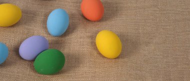 Paskalya yumurtası ya da renkli yumurta. Stüdyoda arka planda çok renkli paskalya yumurtaları var. Yakın plan çekimde sarı, yeşil, mavi, mor, festival yumurtalarının üzerine resim yaparken kırmızı renkler kullanılıyor..