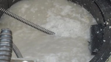 Kanalizasyon temizliği. Tesisatçı, tıkanmış yağ tutucuyu makineyle tamir ediyor. Profesyonel tesisatçı tarafından kanalizasyon sistemini ve yağ tutucuyu onarmak. Kanalizasyonu tamir etmek ve açmak için çengelli yılan kullanıyor..