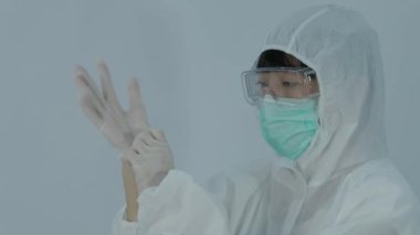 Eldiven takıyordu. PPE ve maskeli doktor plastik nitril eldiven takıyor. Doktorun eldiven taktığı görüntüler. izole edilmiş beyaz arkaplan kopyalama alanı. Sağlık koruma koronovirüs salgını konsepti.