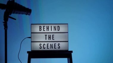 Sinema ışığı kutusundaki sahne arkası mektupları. Sahne arkasındaki beyaz LED ışık kutusu üzerindeki siyah metin. Dekorlar arasında megafon film alkışları ve stüdyoda yönetmen koltuğu var. video yapımı için