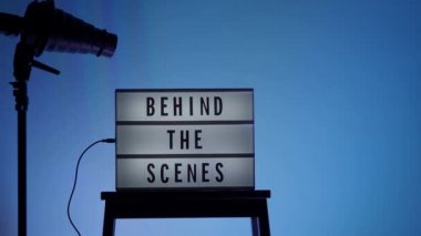 Sinema ışığı kutusundaki sahne arkası mektupları. Sahne arkasındaki beyaz LED ışık kutusu üzerindeki siyah metin. Dekorlar arasında megafon film alkışları ve stüdyoda yönetmen koltuğu var. video yapımı için