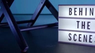 Sinema ışığı kutusundaki sahne arkası mektupları. Sahne arkasındaki beyaz LED ışık kutusu üzerindeki siyah metin. Dekorlar arasında megafon film alkışları ve stüdyoda yönetmen koltuğu var. video yapımı için