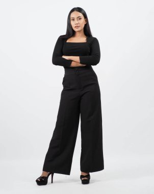 Asyalı kadın tüm vücudu. Modern şık tarzda Taylandlı bir kadın zarif ve kendine güvenen duruşu olan beyaz bir stüdyoda duruyor. Oyuncu kadrosu yardımcı oyuncu. Kameranın önünde Asyalı kadın pozu.