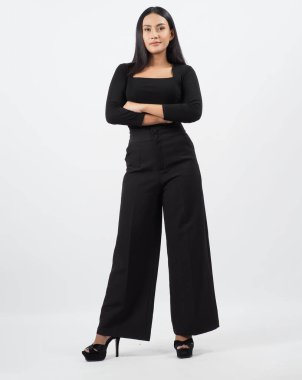 Asyalı kadın tüm vücudu. Modern şık tarzda Taylandlı bir kadın zarif ve kendine güvenen duruşu olan beyaz bir stüdyoda duruyor. Oyuncu kadrosu yardımcı oyuncu. Kameranın önünde Asyalı kadın pozu.