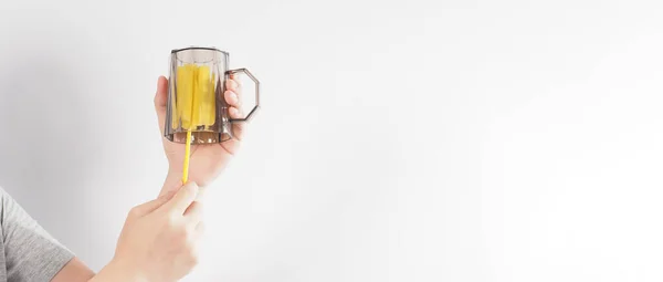 Clean and wash dish concept. Man hand washing drink glass on white background. Used drinking glass cleaning by soft yellow sponge stick. Wash cup by sponge brush. Disinfection hyginic in covid 19 era