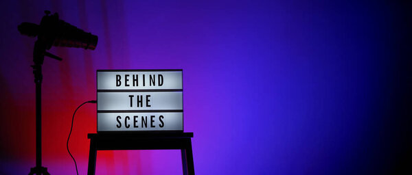 За кадром текст на Lightbox или Cinema Light поле. Лайтбокс Movie на студийной панели и легкий штатив Snoot на цветовом фоне. Представители закулисной команды работают над.