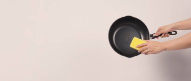 Elektrikli tencere temizleme. El beyaz arka plan temizleme çubuk olmayan tava kullanışlı bulaşık sünger ile yumuşak tarafında sarı renk ve pişirdikten sonra hijyen için sert tarafta yeşil.