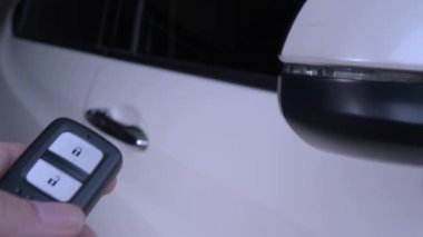 Araba anahtarı uzaktan kumandası. Arabanın uzaktan kumandasının yanındaki kilidi açıp kapatıyorum. Araba anahtarının düğmesine basıyorum ve kapılar açılıp kapandığında ışıklar yanıp sönüyor. Uzaktan kumanda kullanan insan eli.