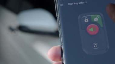 Unlock and lock Car Using Smartphone App. Man hand Unlocking car by use mobile application on a smart phone. Key remote control and car protection through the internet. Car technology with smartphone.