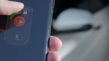 Unlock and lock Car Using Smartphone App. Man hand Unlocking car by use mobile application on a smart phone. Key remote control and car protection through the internet. Car technology with smartphone.