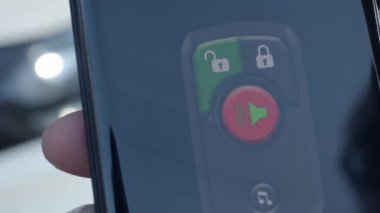 Unlock and lock Car Using Smartphone App. Man hand Unlocking car by use mobile application on a smart phone. Key remote control and car protection through the internet. Car technology with smartphone.