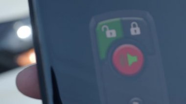 Unlock and lock Car Using Smartphone App. Man hand Unlocking car by use mobile application on a smart phone. Key remote control and car protection through the internet. Car technology with smartphone.