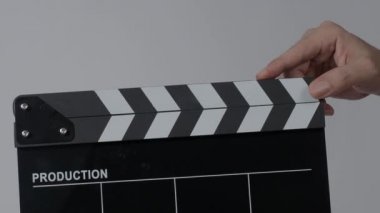 Movie slate or clapperboard hitting. Close up hand holding empty film slate and clapping it. Open and close film slate for video production. film production. color background studio. ready to shoot