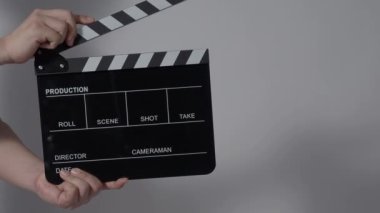 Film tahtası ya da alkış tahtası vuruşu. El ele tutuşup boş film tahtasını tutarak alkışlıyoruz. Video prodüksiyonu için açık ve kapalı film sayfası. Film yapımcılığı. Renkli arka plan stüdyosu Çekime hazır.