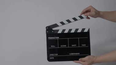 Film tahtası ya da alkış tahtası vuruşu. El ele tutuşup boş film tahtasını tutarak alkışlıyoruz. Video prodüksiyonu için açık ve kapalı film sayfası. Film yapımcılığı. Renkli arka plan stüdyosu Çekime hazır.