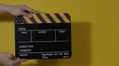 Movie slate or clapperboard hitting. Close up hand holding empty film slate and clapping it. Open and close film slate for video production. film production. color background studio. ready to shoot