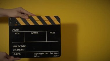 Movie slate or clapperboard hitting. Close up hand holding empty film slate and clapping it. Open and close film slate for video production. film production. color background studio. ready to shoot