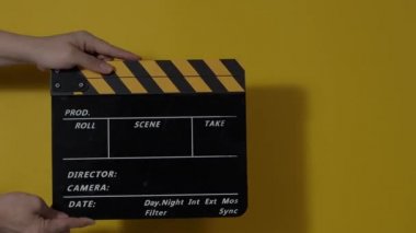 Movie slate or clapperboard hitting. Close up hand holding empty film slate and clapping it. Open and close film slate for video production. film production. color background studio. ready to shoot