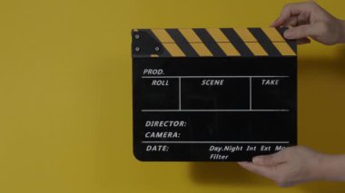 Movie slate or clapperboard hitting. Close up hand holding empty film slate and clapping it. Open and close film slate for video production. film production. color background studio. ready to shoot