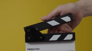 Movie slate or clapperboard hitting. Close up hand holding empty film slate and clapping it. Open and close film slate for video production. film production. color background studio. ready to shoot