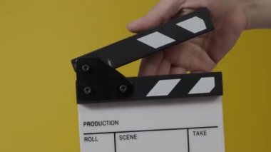 Movie slate or clapperboard hitting. Close up hand holding empty film slate and clapping it. Open and close film slate for video production. film production. color background studio. ready to shoot