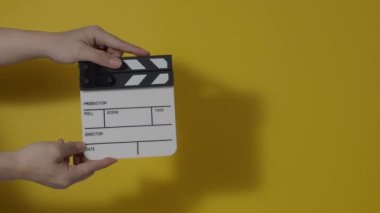 Movie slate or clapperboard hitting. Close up hand holding empty film slate and clapping it. Open and close film slate for video production. film production. color background studio. ready to shoot