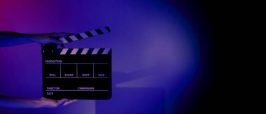 Film tahtası ya da alkışlama tahtasının bulanık görüntüleri. Stüdyoda film çekimi ya da kayıt için renk arkaplanı üzerinde el ele tutuşan boş bir film. Youtuber video üretimi için film tahtası.