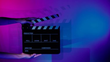 Film tahtası ya da alkışlama tahtasının bulanık görüntüleri. Stüdyoda film çekimi ya da kayıt için renk arkaplanı üzerinde el ele tutuşan boş bir film. Youtuber video üretimi için film tahtası.