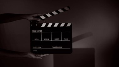 Blurry images of movie slate or clapper board. Hand holds empty film making clapperboard on color background in studio for film movie shooting or recording. Film slate for Youtuber video production. clipart