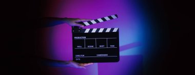 Film tahtası ya da alkışlama tahtasının bulanık görüntüleri. Stüdyoda film çekimi ya da kayıt için renk arkaplanı üzerinde el ele tutuşan boş bir film. Youtuber video üretimi için film tahtası.
