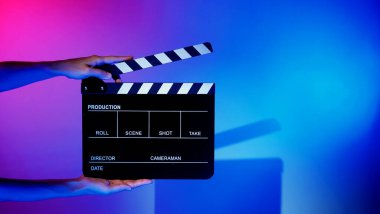 Film tahtası ya da alkışlama tahtasının bulanık görüntüleri. Stüdyoda film çekimi ya da kayıt için renk arkaplanı üzerinde el ele tutuşan boş bir film. Youtuber video üretimi için film tahtası.