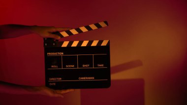 Film tahtası ya da alkışlama tahtasının bulanık görüntüleri. Stüdyoda film çekimi ya da kayıt için renk arkaplanı üzerinde el ele tutuşan boş bir film. Youtuber video üretimi için film tahtası.
