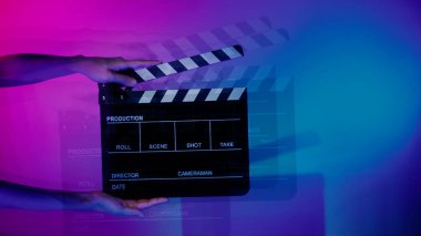 Film tahtası ya da alkışlama tahtasının bulanık görüntüleri. Stüdyoda film çekimi ya da kayıt için renk arkaplanı üzerinde el ele tutuşan boş bir film. Youtuber video üretimi için film tahtası.