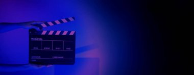Film tahtası ya da alkışlama tahtasının bulanık görüntüleri. Stüdyoda film çekimi ya da kayıt için renk arkaplanı üzerinde el ele tutuşan boş bir film. Youtuber video üretimi için film tahtası.