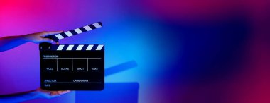 Film tahtası ya da alkışlama tahtasının bulanık görüntüleri. Stüdyoda film çekimi ya da kayıt için renk arkaplanı üzerinde el ele tutuşan boş bir film. Youtuber video üretimi için film tahtası.