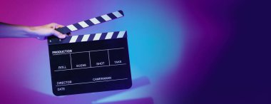 Film tahtası ya da alkışlama tahtasının bulanık görüntüleri. Stüdyoda film çekimi ya da kayıt için renk arkaplanı üzerinde el ele tutuşan boş bir film. Youtuber video üretimi için film tahtası.