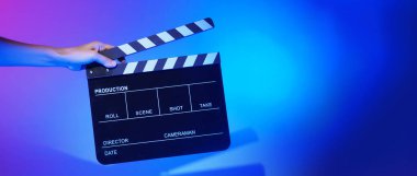 Film tahtası ya da alkışlama tahtasının bulanık görüntüleri. Stüdyoda film çekimi ya da kayıt için renk arkaplanı üzerinde el ele tutuşan boş bir film. Youtuber video üretimi için film tahtası.