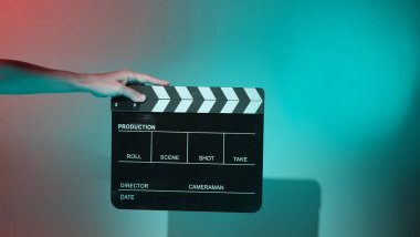 Film tahtası ya da alkışlama tahtasının bulanık görüntüleri. Stüdyoda film çekimi ya da kayıt için renk arkaplanı üzerinde el ele tutuşan boş bir film. Youtuber video üretimi için film tahtası.