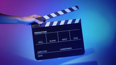 Film tahtası ya da alkışlama tahtasının bulanık görüntüleri. Stüdyoda film çekimi ya da kayıt için renk arkaplanı üzerinde el ele tutuşan boş bir film. Youtuber video üretimi için film tahtası.