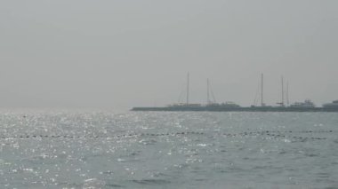 Deniz dalgaları ve mavi gökyüzü. Rüzgârla dalgalanan deniz. Mavi deniz dalgası. Tayland 'ın ünlü deniz mekanlarından biri olan Pattaya plajı. Denizdeki yat limanı limanı. Tatili rahatlatıcı bir şekilde temsil et. Statik Kamera.