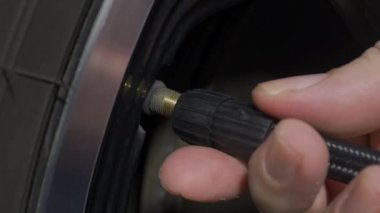 Lastik şişiyor. Seyahatten önce lastikleri dolduruyorum. Adam sürmeden önce vananın kapağını açıp araba lastiğini şişiriyor. Gösterge kullanarak araba tekerleği hava basıncını kontrol ediyorum. Otomotiv aracı. Araba tekerleği hava tamiri.