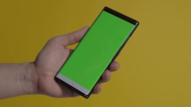 Akıllı telefon ekranı. Akıllı telefon renk arkaplanında izole edilmiş. Yeşil ekran krom anahtar tekniği. Adamın eli cep telefonunun yeşil ekranına değdi. Akıllı telefon ekranını kullanarak. El hareketleriyle. 4K görüntü.