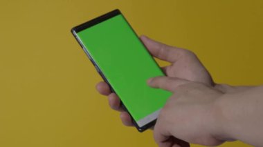 Akıllı telefon ekranı. Akıllı telefon renk arkaplanında izole edilmiş. Yeşil ekran krom anahtar tekniği. Adamın eli cep telefonunun yeşil ekranına değdi. Akıllı telefon ekranını kullanarak. El hareketleriyle. 4K görüntü.