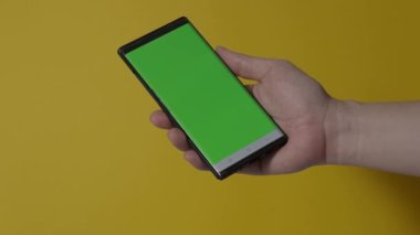 Akıllı telefon ekranı. Akıllı telefon renk arkaplanında izole edilmiş. Yeşil ekran krom anahtar tekniği. Adamın eli cep telefonunun yeşil ekranına değdi. Akıllı telefon ekranını kullanarak. El hareketleriyle. 4K görüntü.