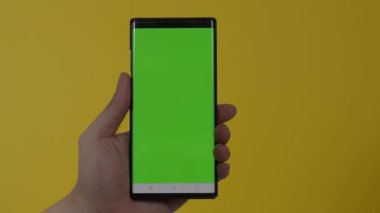 Akıllı telefon ekranı. Akıllı telefon renk arkaplanında izole edilmiş. Yeşil ekran krom anahtar tekniği. Adamın eli cep telefonunun yeşil ekranına değdi. Akıllı telefon ekranını kullanarak. El hareketleriyle. 4K görüntü.