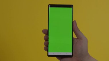 Akıllı telefon ekranı. Akıllı telefon renk arkaplanında izole edilmiş. Yeşil ekran krom anahtar tekniği. Adamın eli cep telefonunun yeşil ekranına değdi. Akıllı telefon ekranını kullanarak. El hareketleriyle. 4K görüntü.