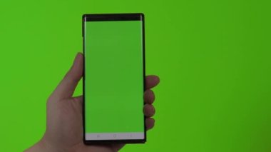 Akıllı telefon ekranı. Akıllı telefon renk arkaplanında izole edilmiş. Yeşil ekran krom anahtar tekniği. Adamın eli cep telefonunun yeşil ekranına değdi. Akıllı telefon ekranını kullanarak. El hareketleriyle. 4K görüntü.