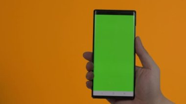 Akıllı telefon ekranı. Akıllı telefon renk arkaplanında izole edilmiş. Yeşil ekran krom anahtar tekniği. Adamın eli cep telefonunun yeşil ekranına değdi. Akıllı telefon ekranını kullanarak. El hareketleriyle. 4K görüntü.